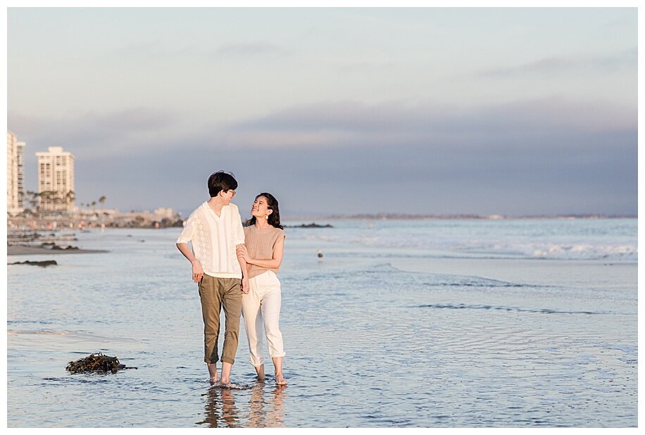 engaged couple walking in ocean at coronado