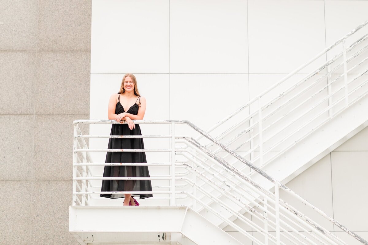 a girl in a black dress posing on a staircase