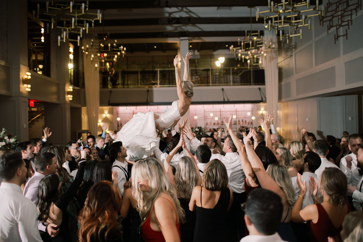 bride being thrown up in crowd during wedding reception