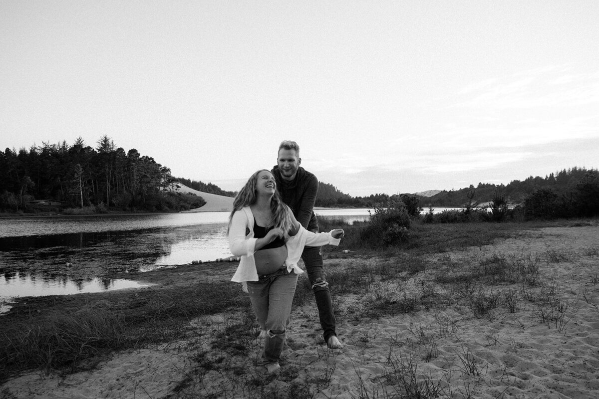 Man and woman laughingly chase each other on the beach.
