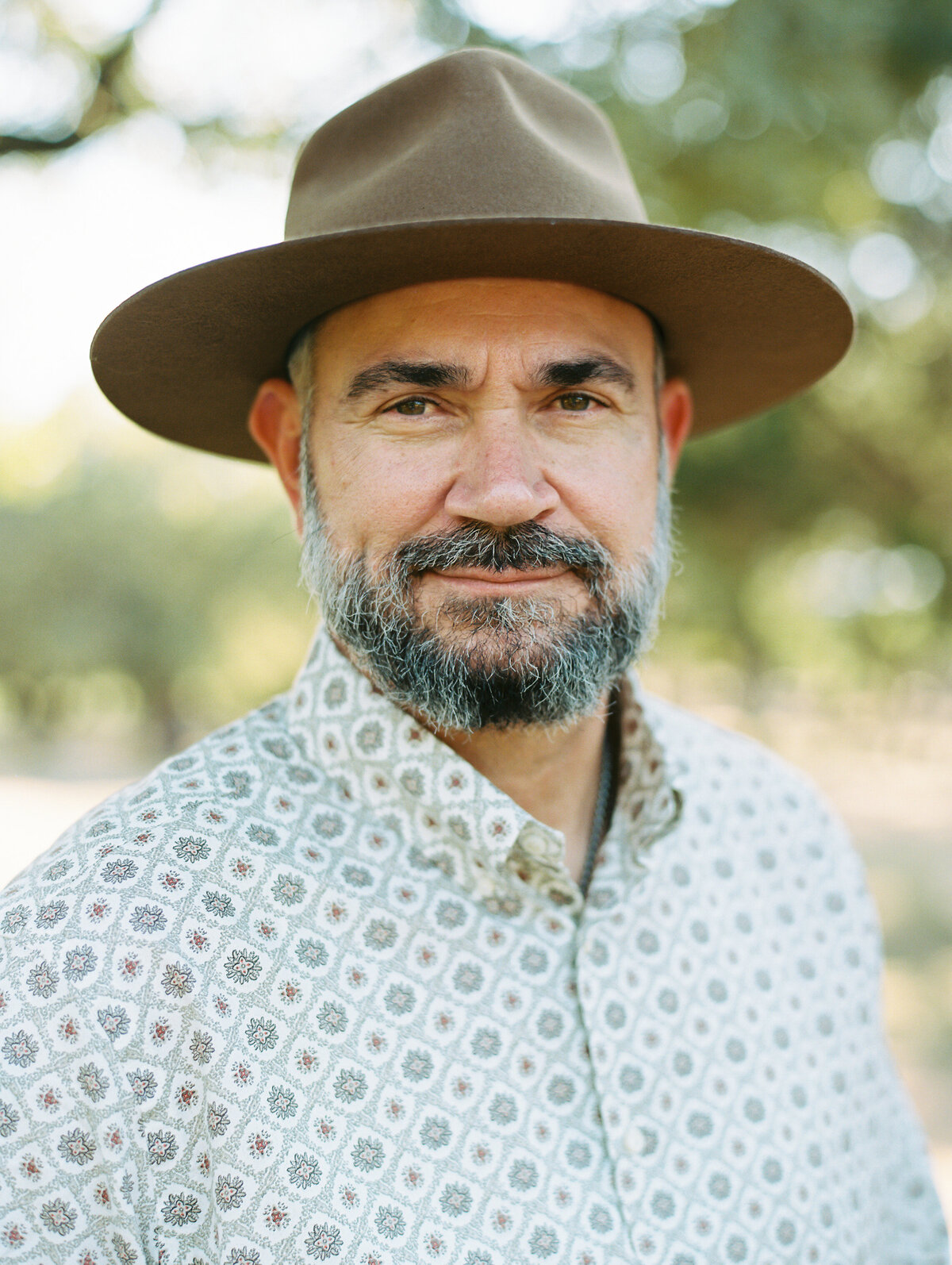 Close up portrait of a man with a beard in a patterned shirt and brown hat