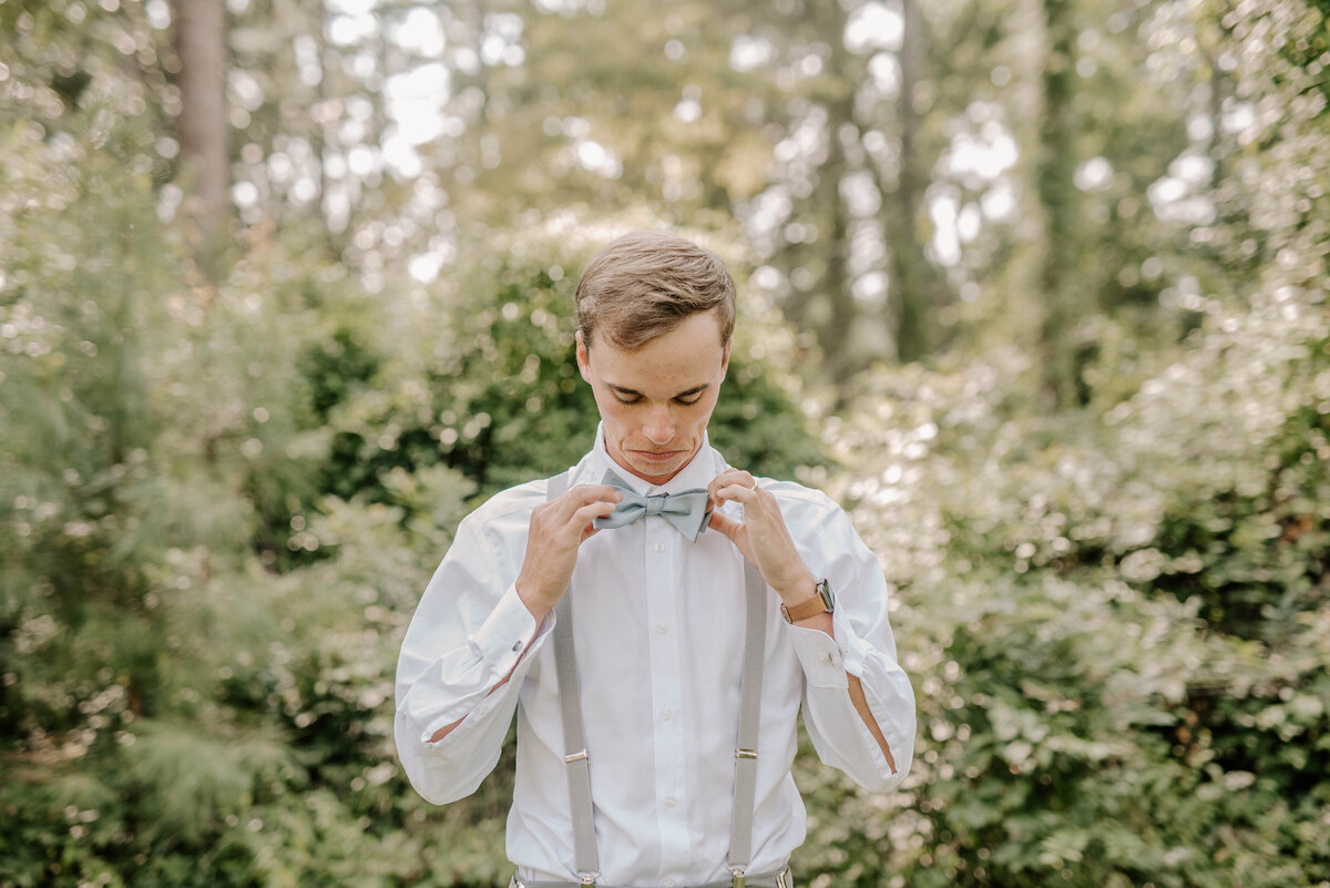 A groom adjusts his bowtie