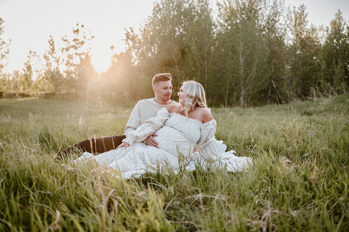 Maternity Pregnant Woman sitting with husband in field