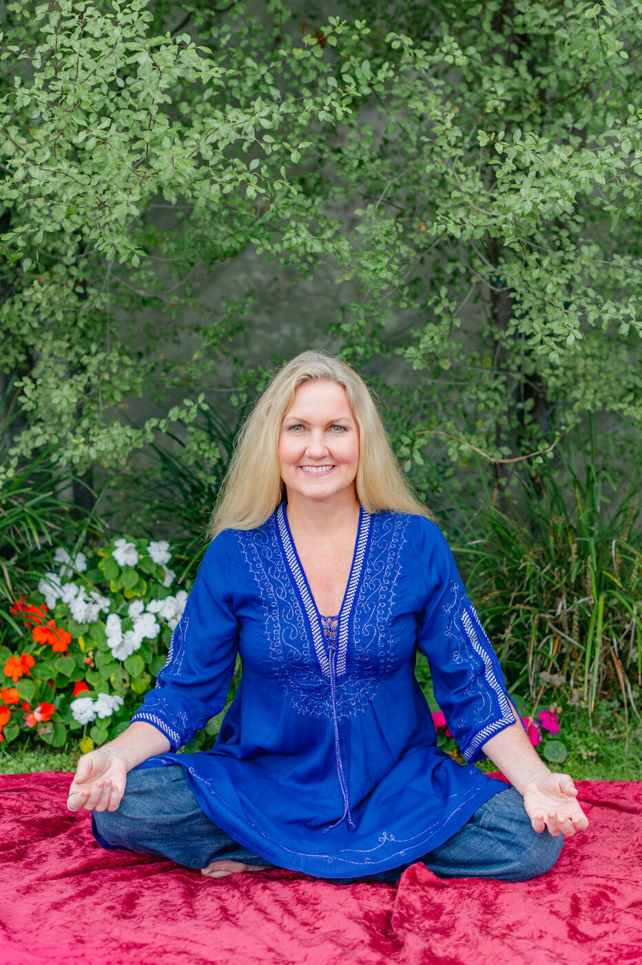 Creative Headshot of a spiritual healer sitting in a yoga pose wearing blue flowing top.