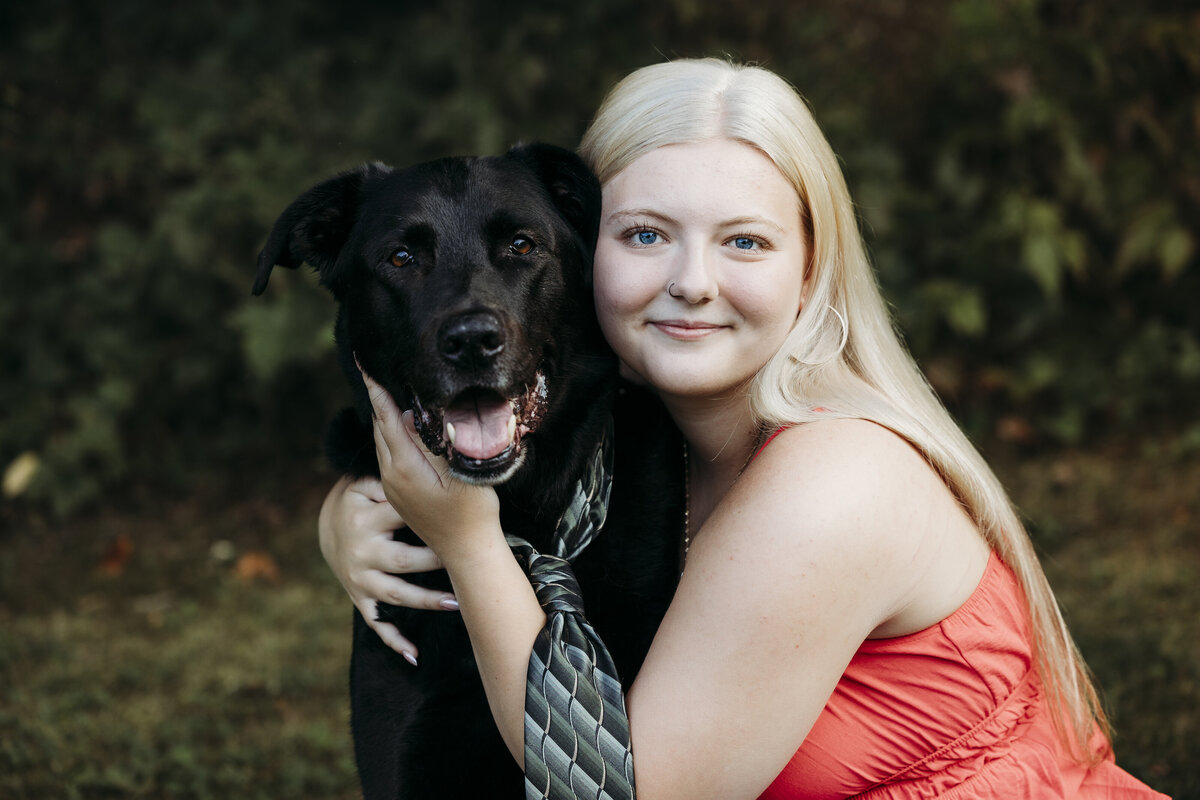 High school girl posing with black lab wearing a tie.