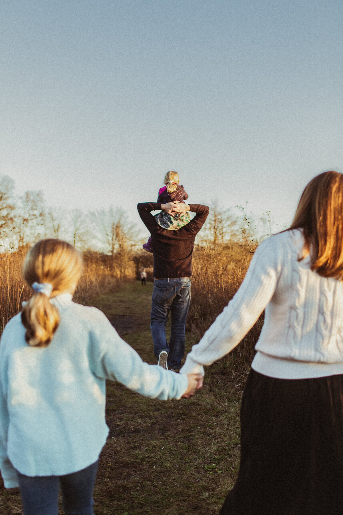 Candid photos of a family walking through a field at sunset.