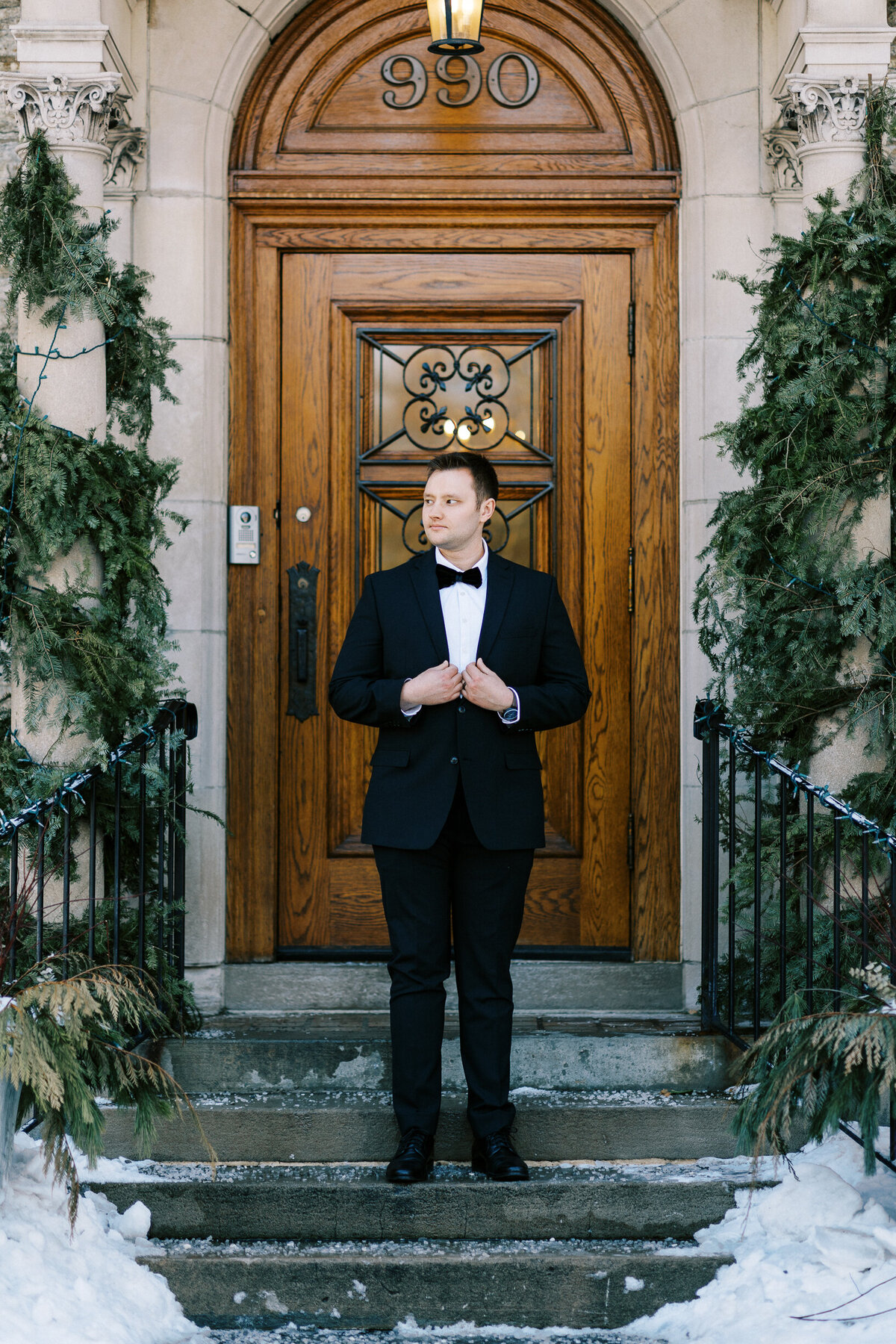 Groom standing at the front door looking away.