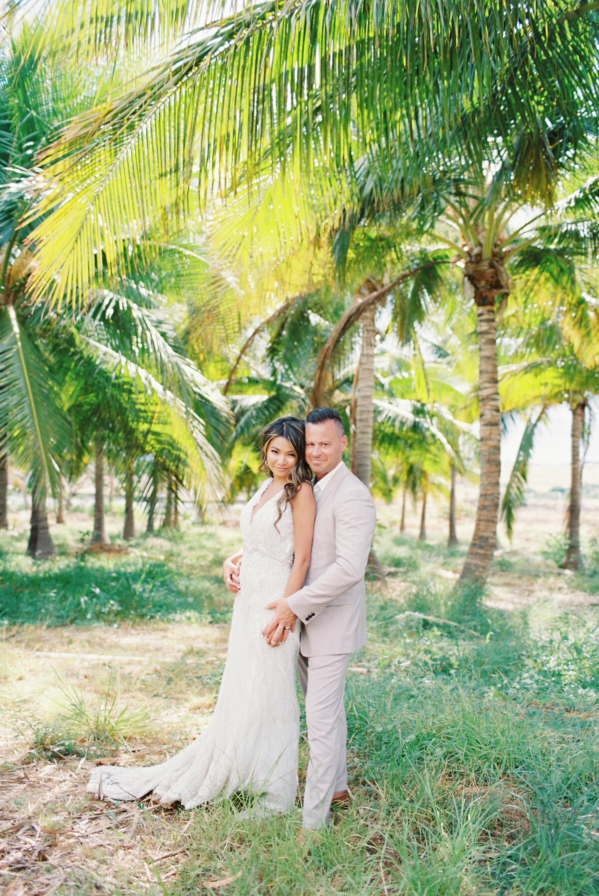 bride and groom in front of palm tree in hawaii