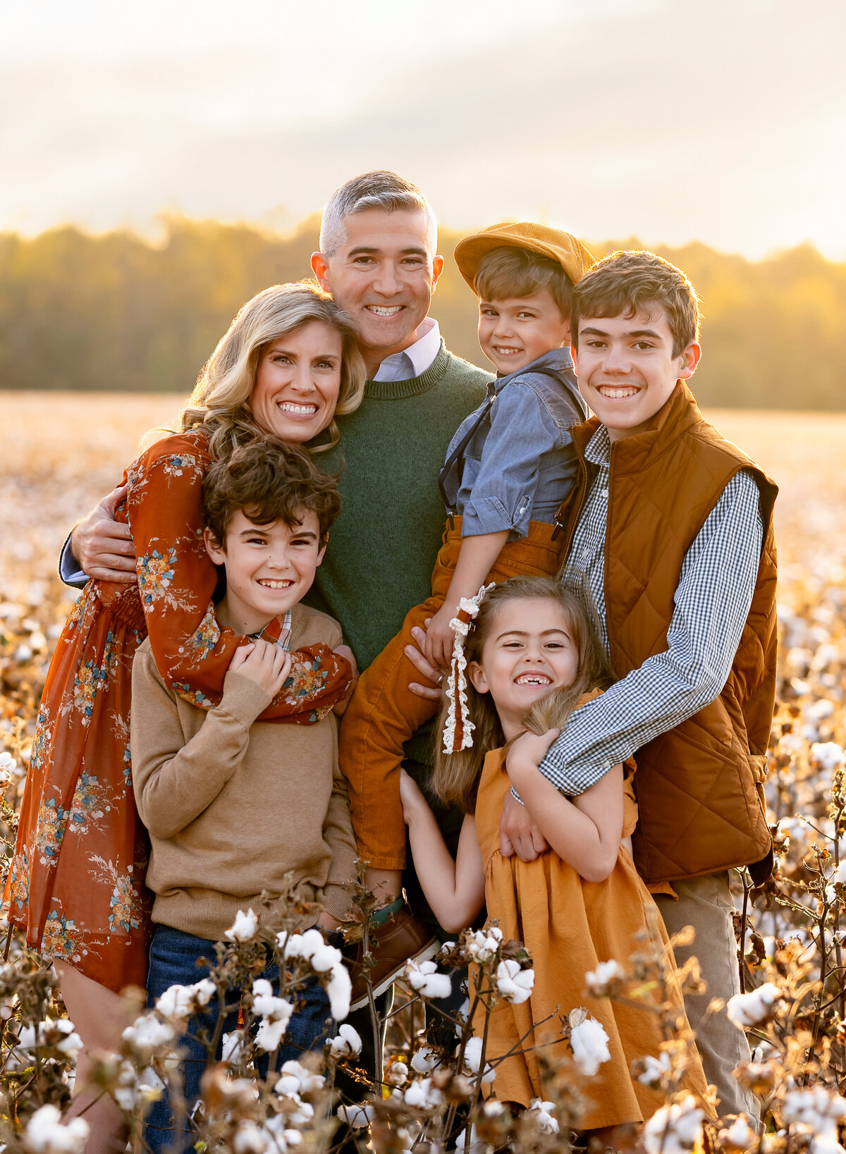 Mom, dad and 4 kids dressed in earthy fall colors and cuddling in a cotton field. Photographed by Atlanta mini session photographer. 
