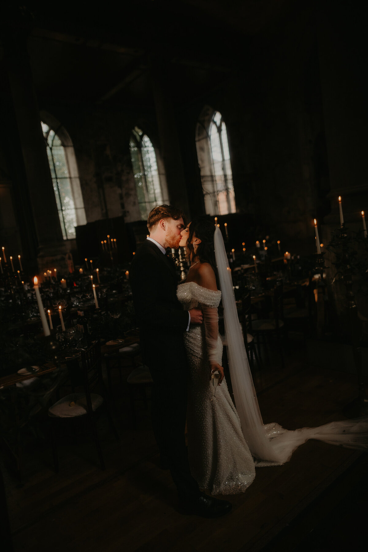 Bride and Groom kiss in the direct sunlight coming through the window at The Mount Without whilst surrounded by candles. 