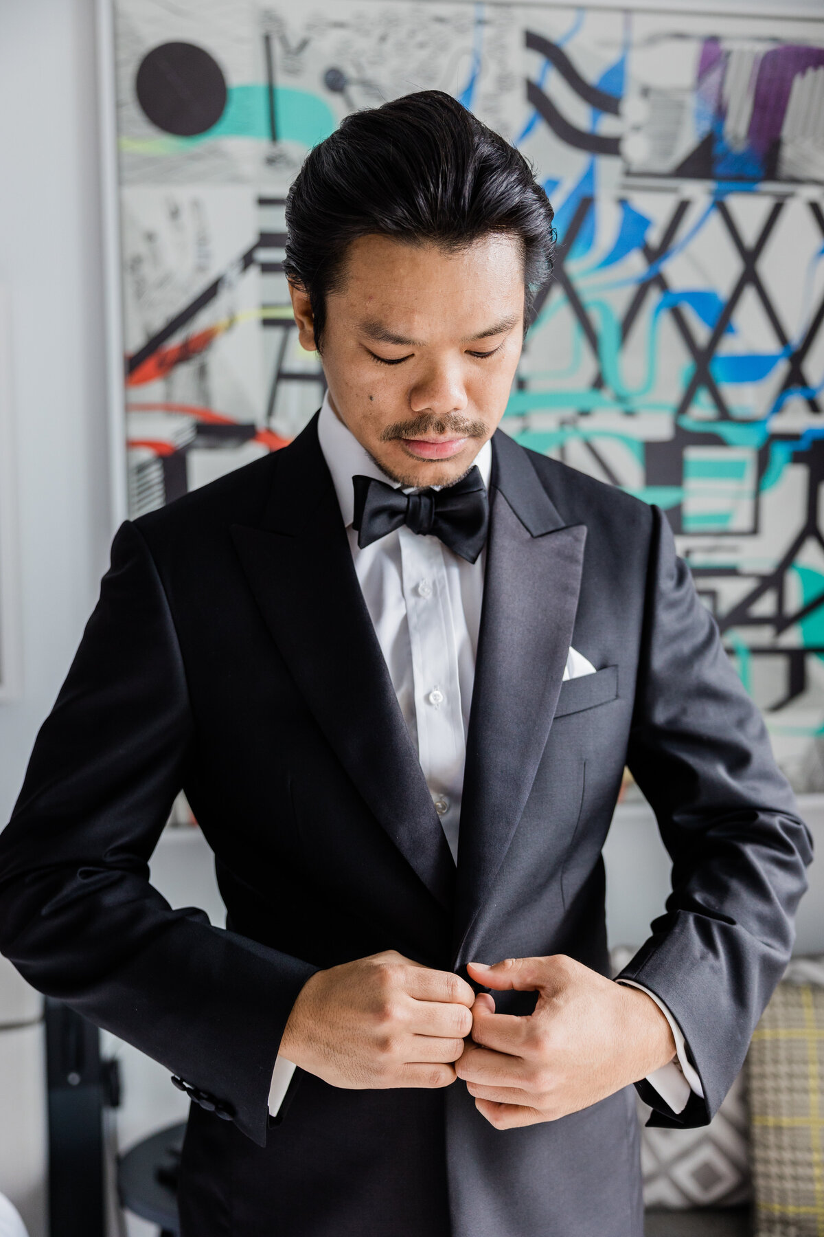 Groom looks down and buttons suit