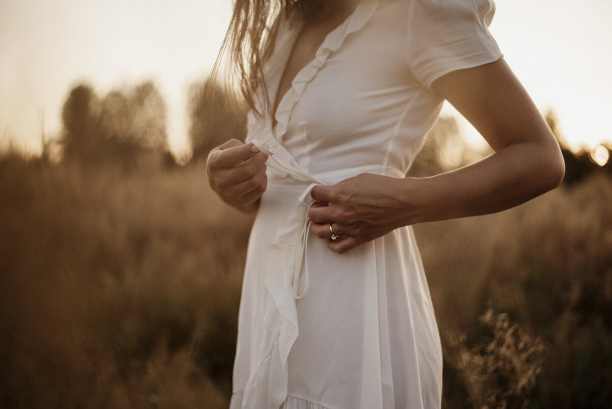 girl tying up the straps of her wrap dress at sunset