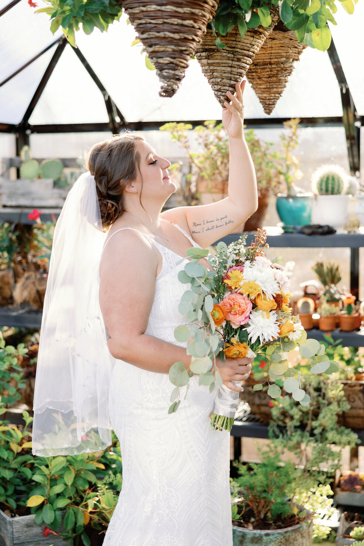A bride posing in a sequin white dress in a greenhouse for portraits at Carolina Home and Garden