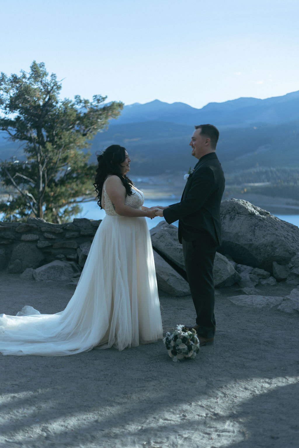 A newlywed couple holding hands and smiling.