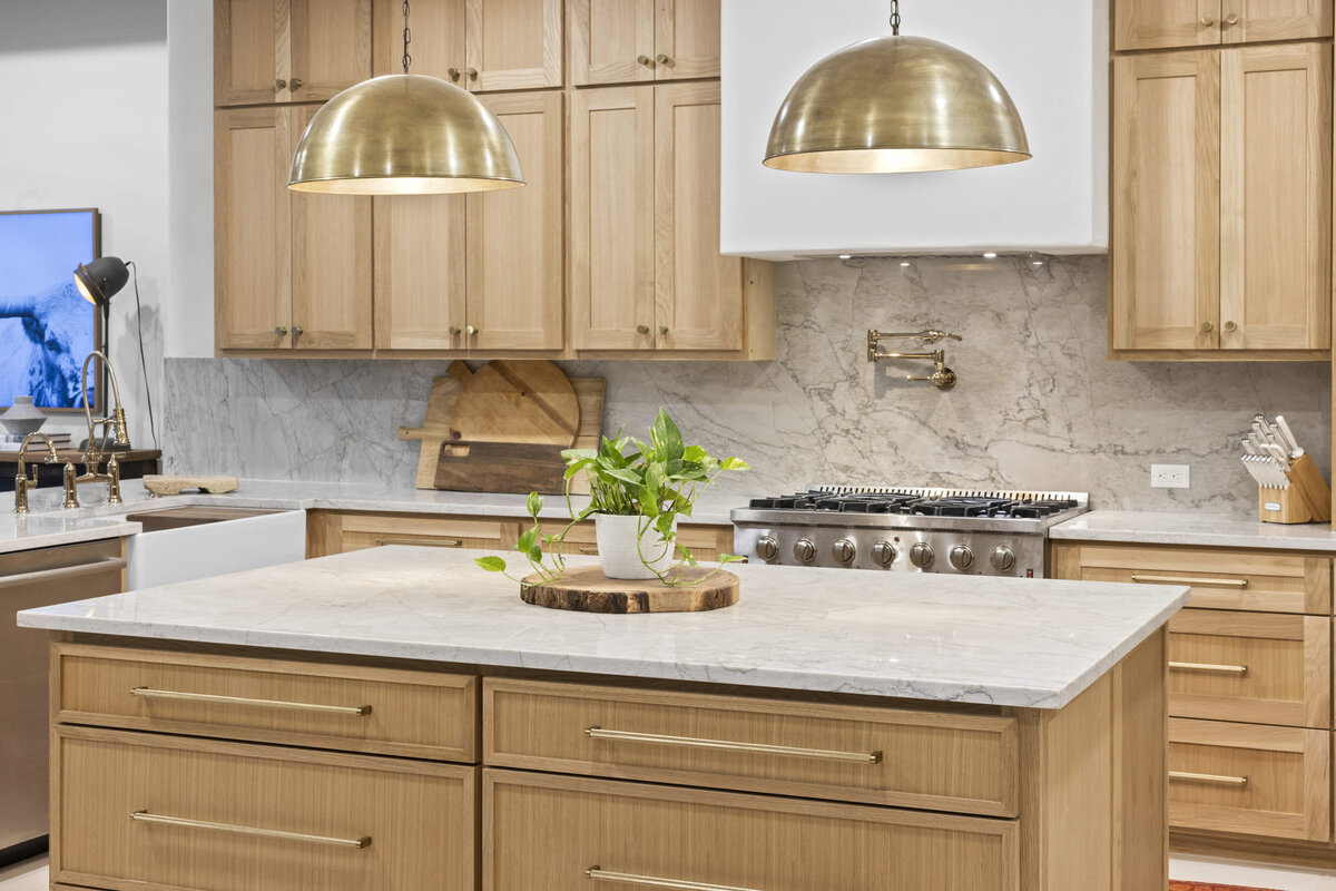 Wooden kitchen with 2 golden lampshapes hanging over island