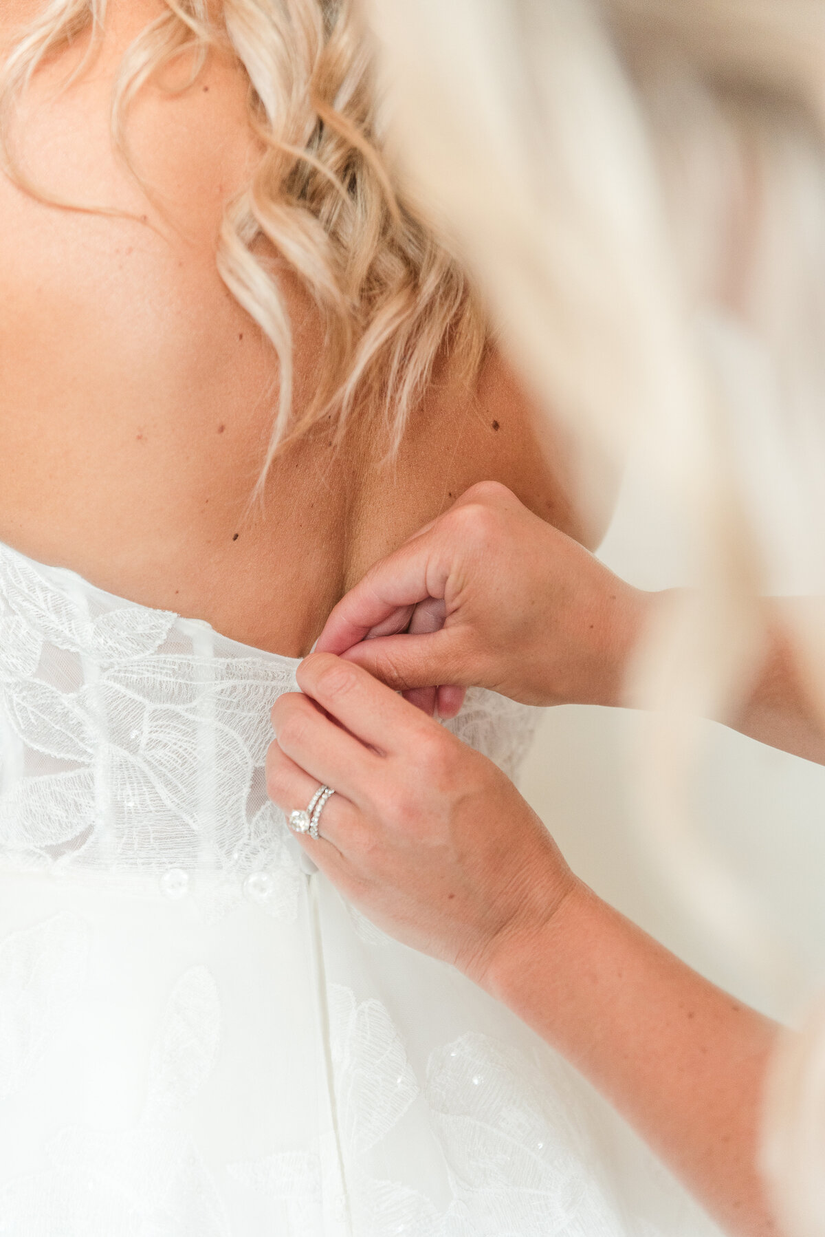 close up of maid of honor butonning bridal gown kent island resort
