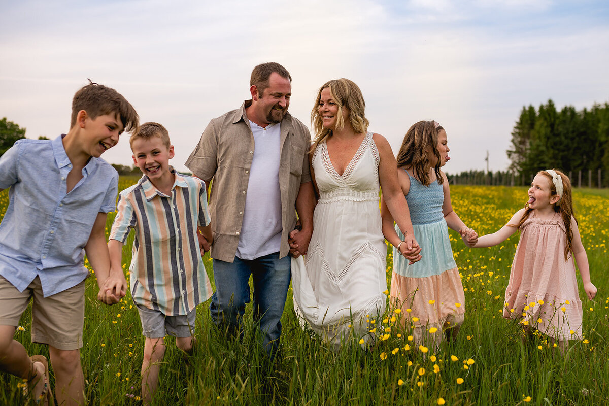 Blended family working together in a field, laughing and enjoying a sunny day in Sawyerville, Quebec, during a joyful family photo session