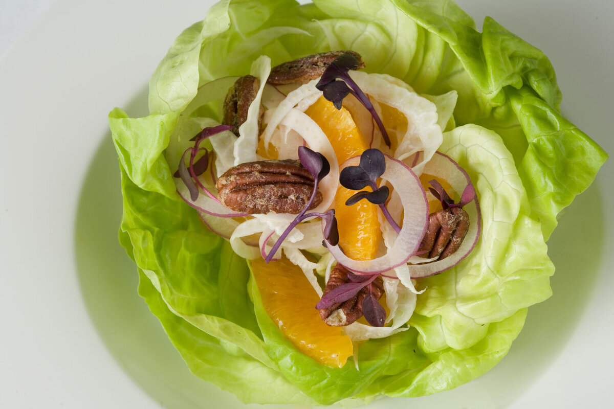 A salad in a lettuce leaf with oranges , onions and pecans