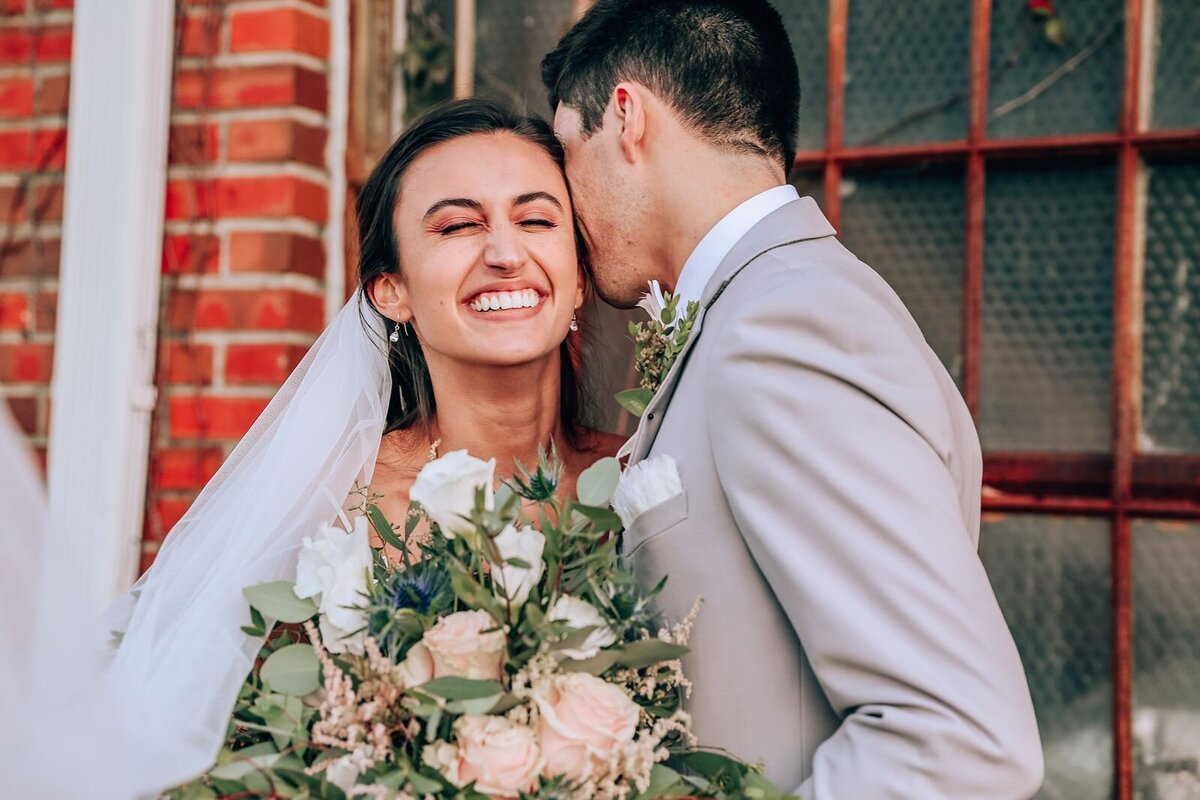 candid moment of bride laughing after groom whispers in her ear