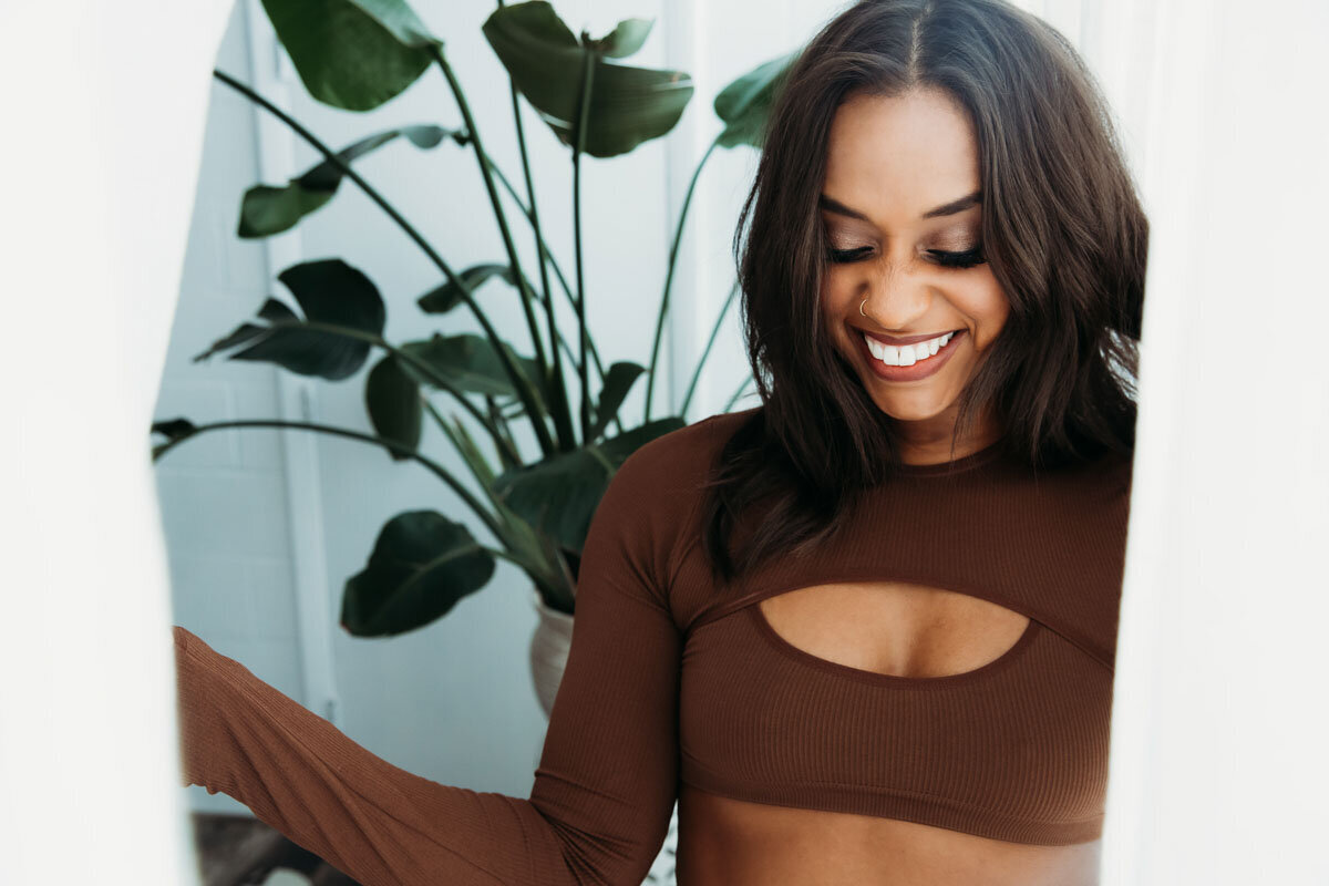 Beauty portrait of black woman pulling back white curtains