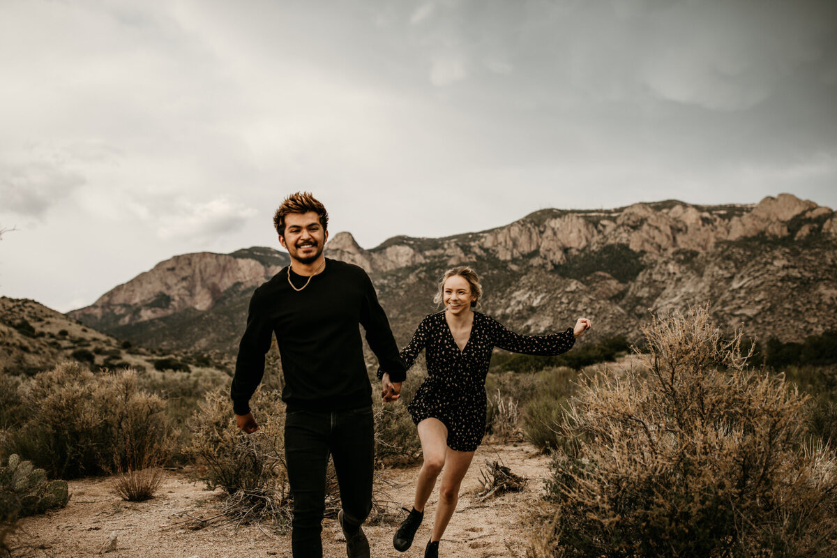 engaged couple running in the Albuquerque desert