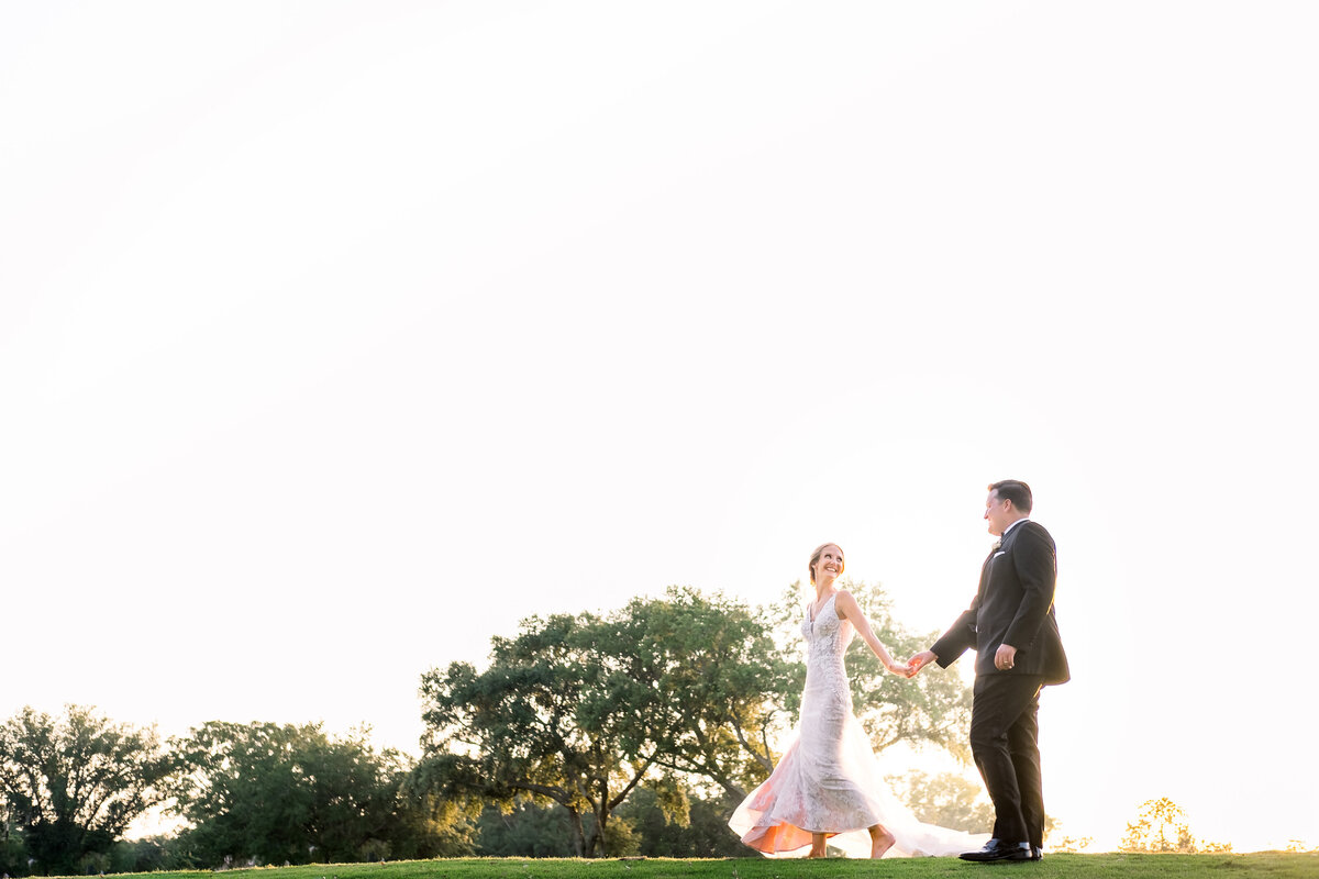 Bride and Groom hold hands as they walk across the Golf Course in Orlando, FL