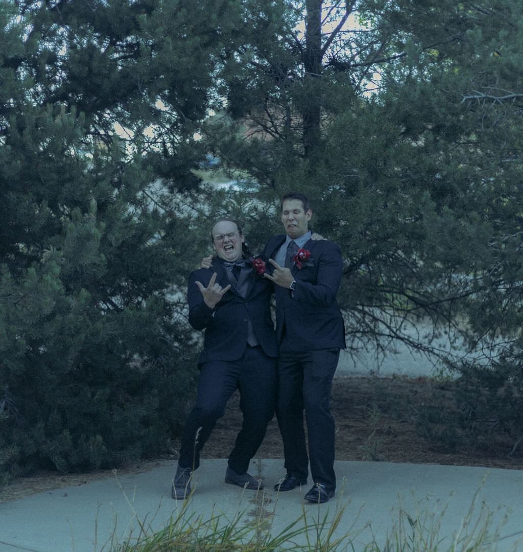 Two people in suits giving rock on symbols.