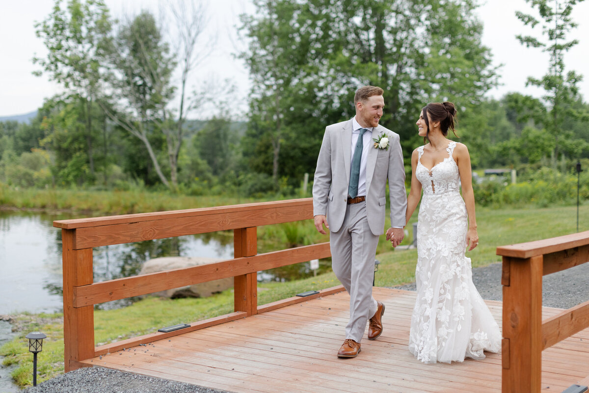 Bride and groom walk hand and hand across a bridge