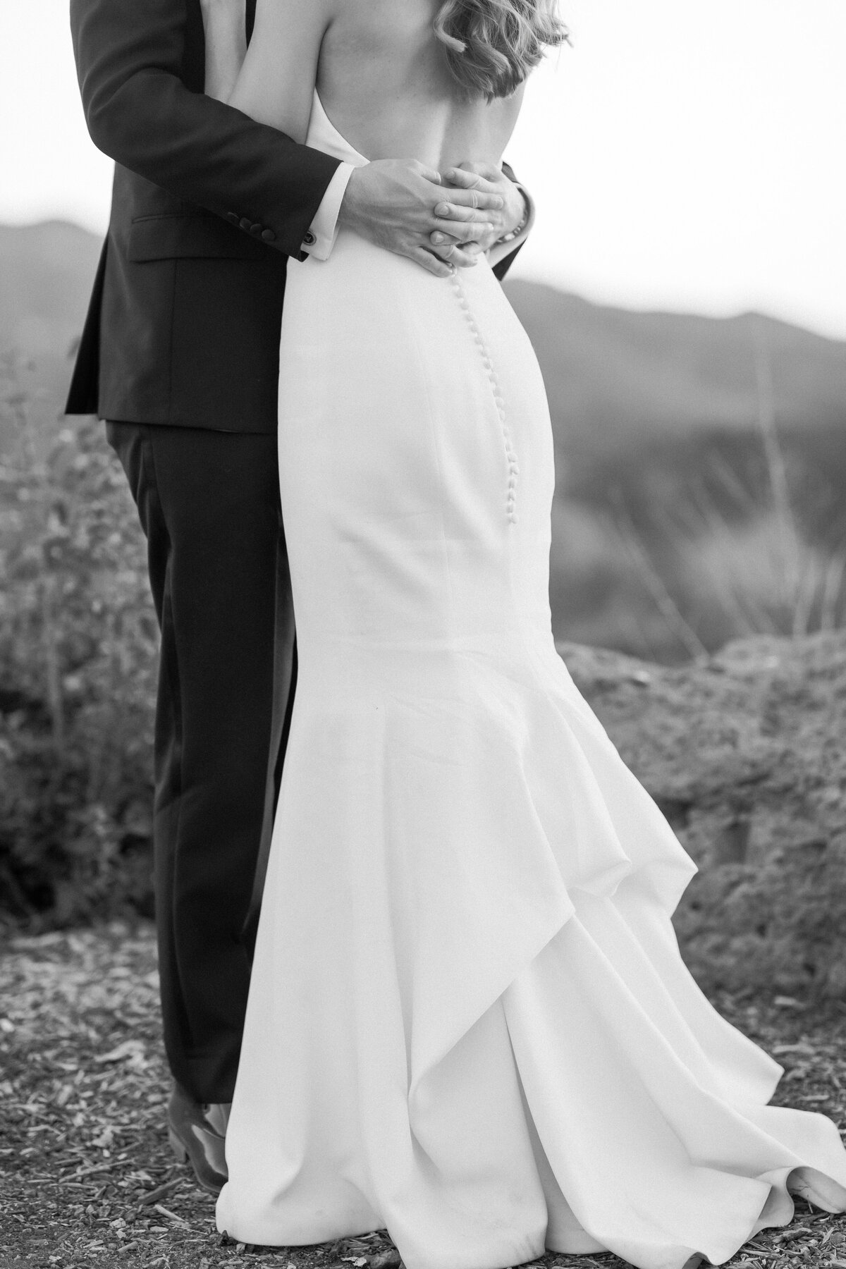 Close up of back of wedding gown as bride and groom embrace