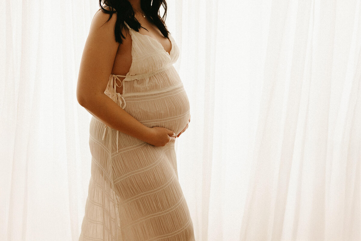 mom holding baby bump while backlit in nashville studio 