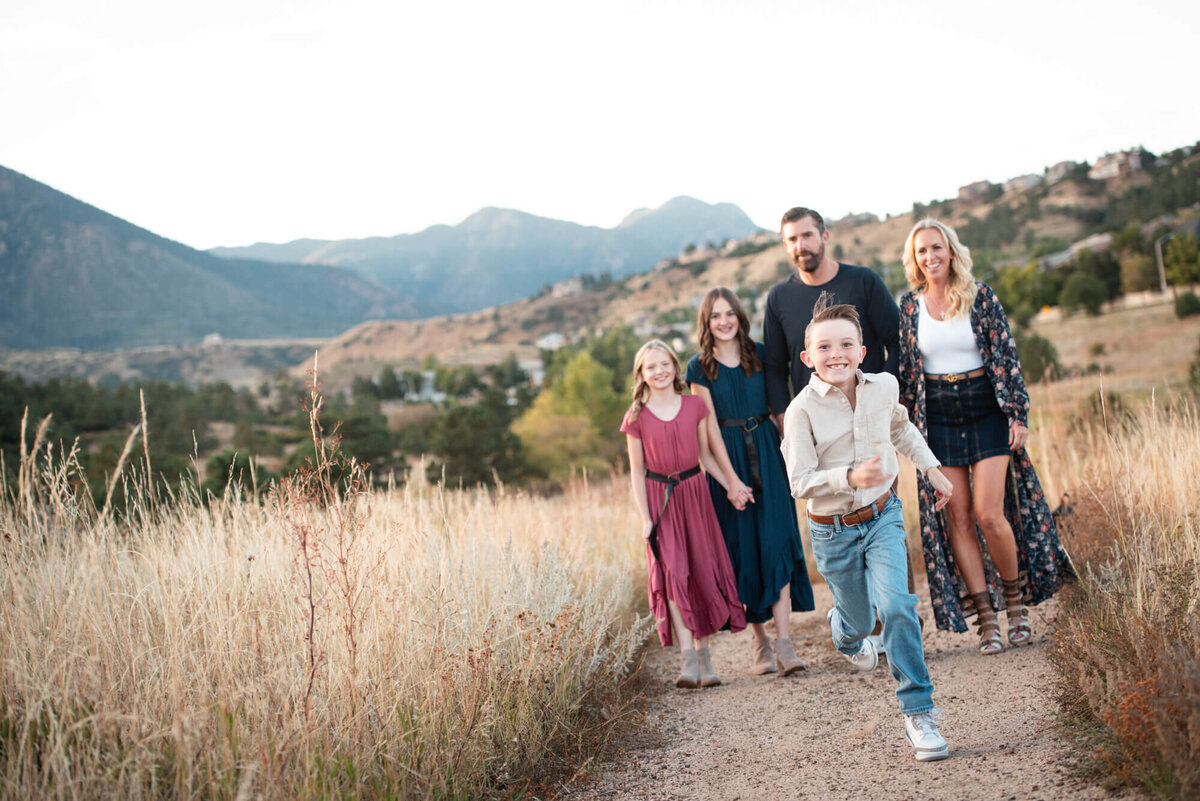 An image taken from a Denver family photographer of a boy running up a trail away from his family behind him