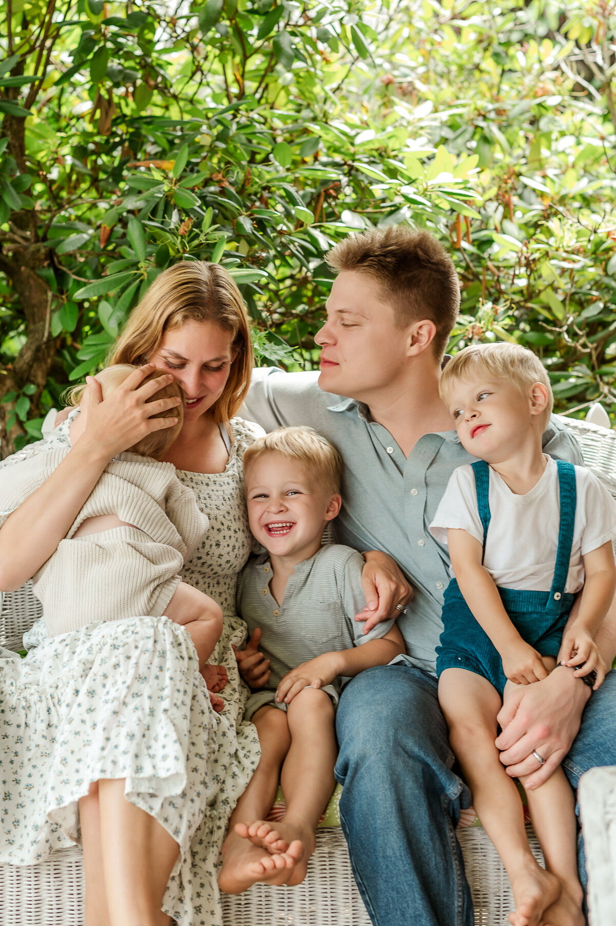 family of five sitting together on their porch smiling and laughing by york and lancaster pa photographer