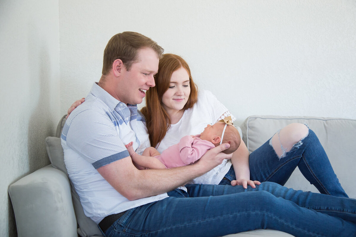 redheaded couple holding baby girl on couch, interacting