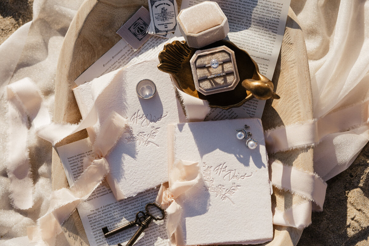Wedding day details including rings and florals on ivory lace fabric.