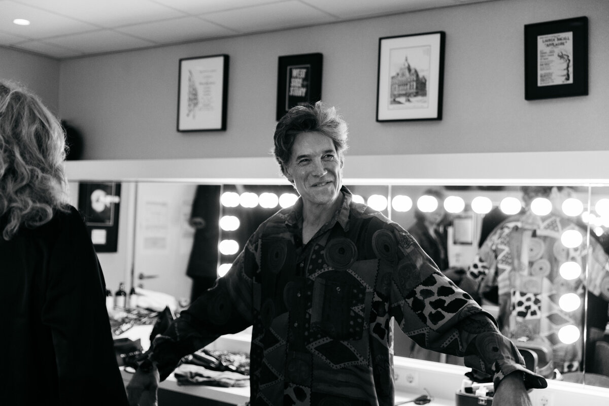 Portret backstage van man in kleedkamer met een lach.