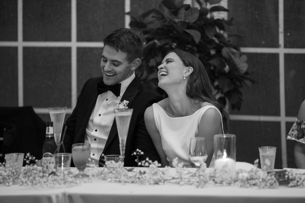 bride and groom laugh during the speeches