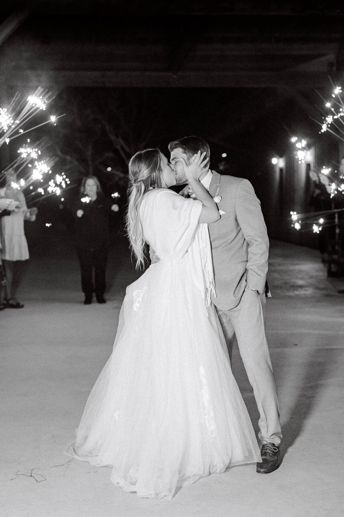 Bride and groom kiss during their sparkler exit at January wedding in Texas
