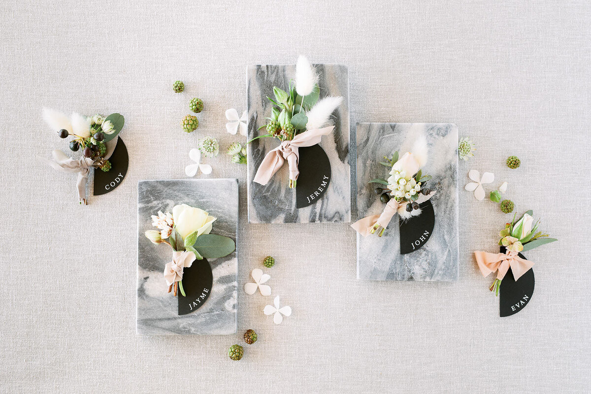 Flat lay image of modern boutonnieres on marble tiles