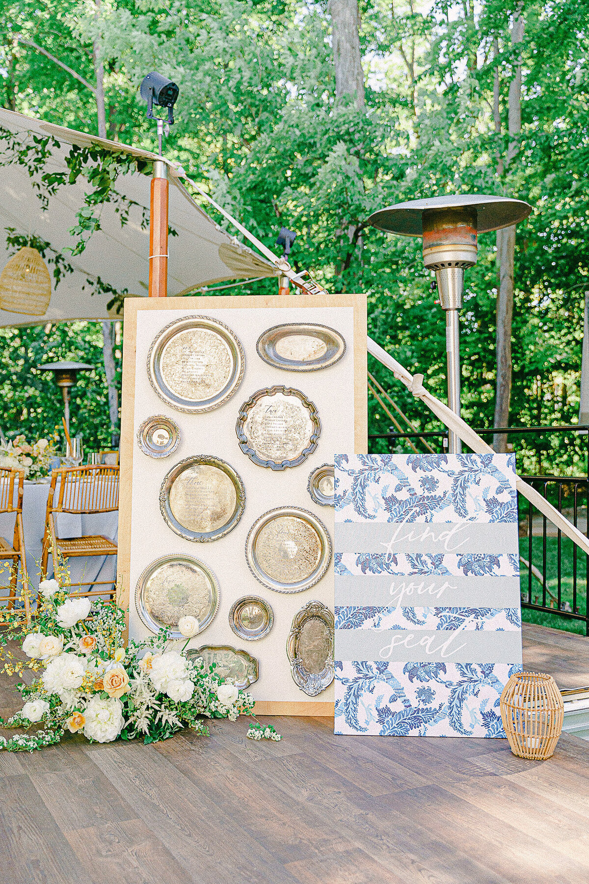 Escort wall made out of vintage serving platters at an intimate tented estate wedding reception