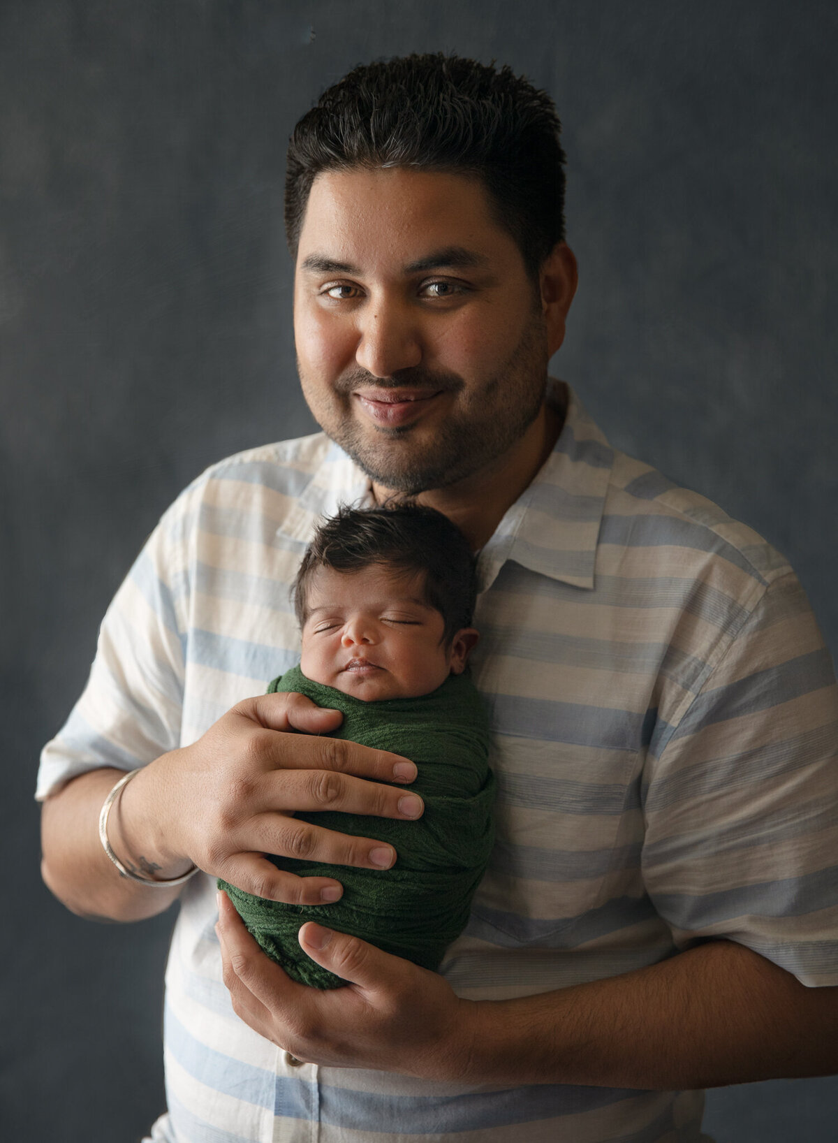 proud father with his baby son in a green wrap and heaps of hair