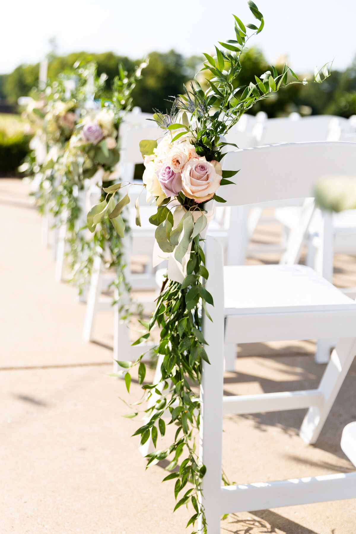 Wedding chairs decorated with greenery and roses at wedding at Stones River Country Club