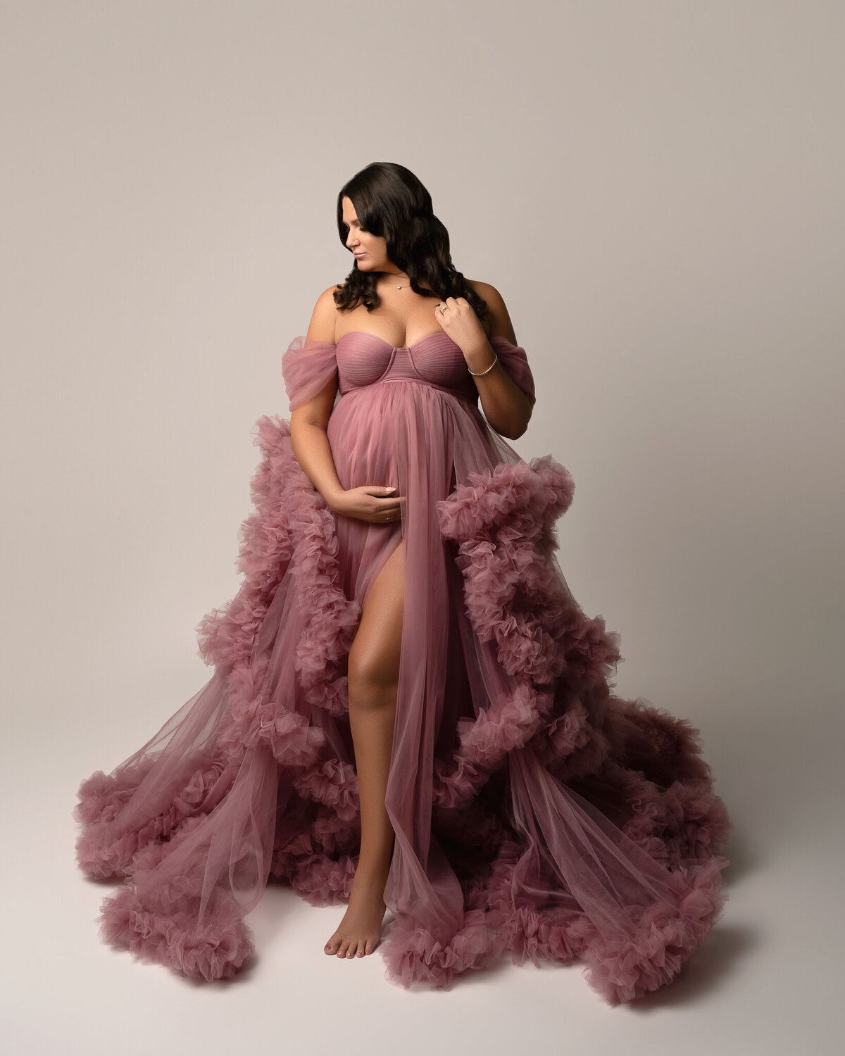 Studio maternity photo of a pregnant woman in a pink ruffled tulle gown, captured in Georgetown, Texas.