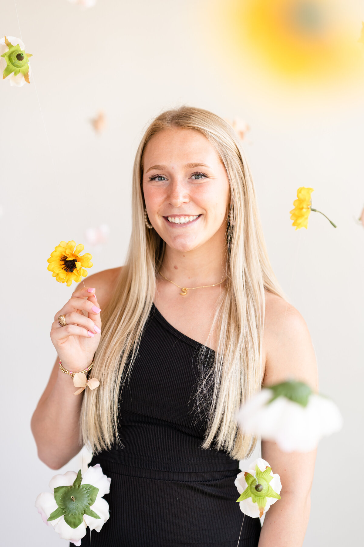 Senior girl smiling in middle of hanging garden while wearing black dress at Bravely Studio