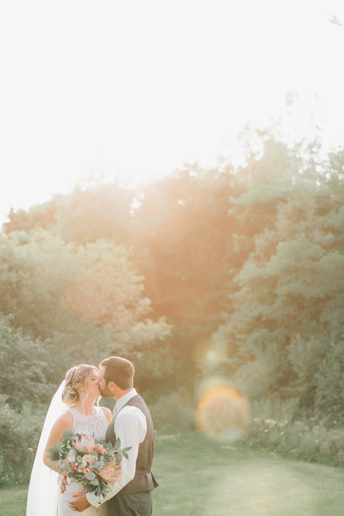 A bride and groom kissing at sunset