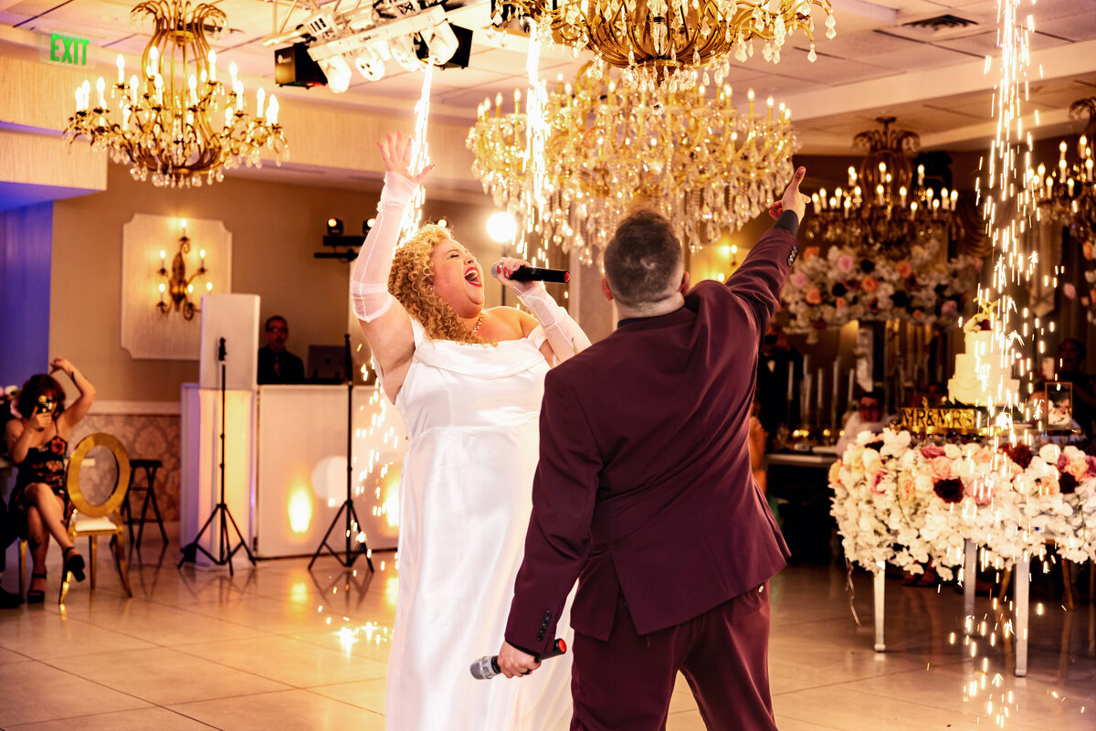 Shannon Lee, from Love Like Wild Photography, captures a bride and groom joyfully singing together under sparkling lights at their wedding reception.