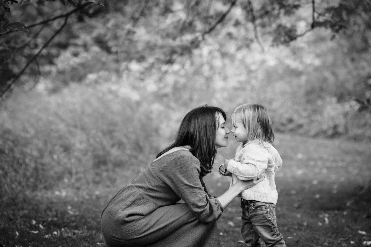 A mom and child are nose to nose outdoors