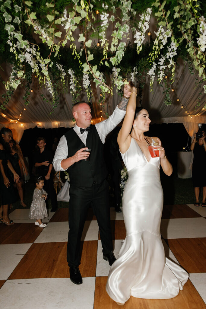 A romantic first dance moment as the newlyweds sway beneath an elegant canopy of flowers and twinkling lights. Florida Keys wedding photography by Claudia Amalia Photography.