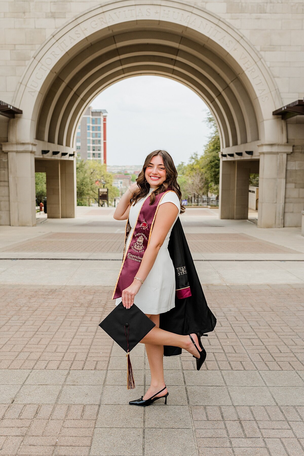 Texas State grad posing at the arch