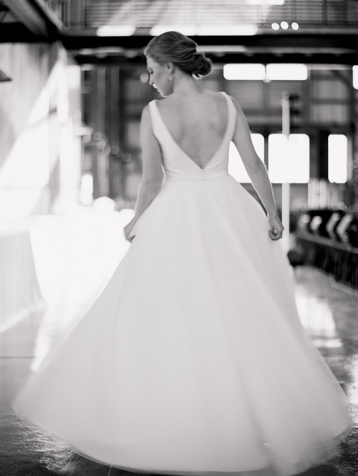 Black and white photo of a bride twirling in her dress