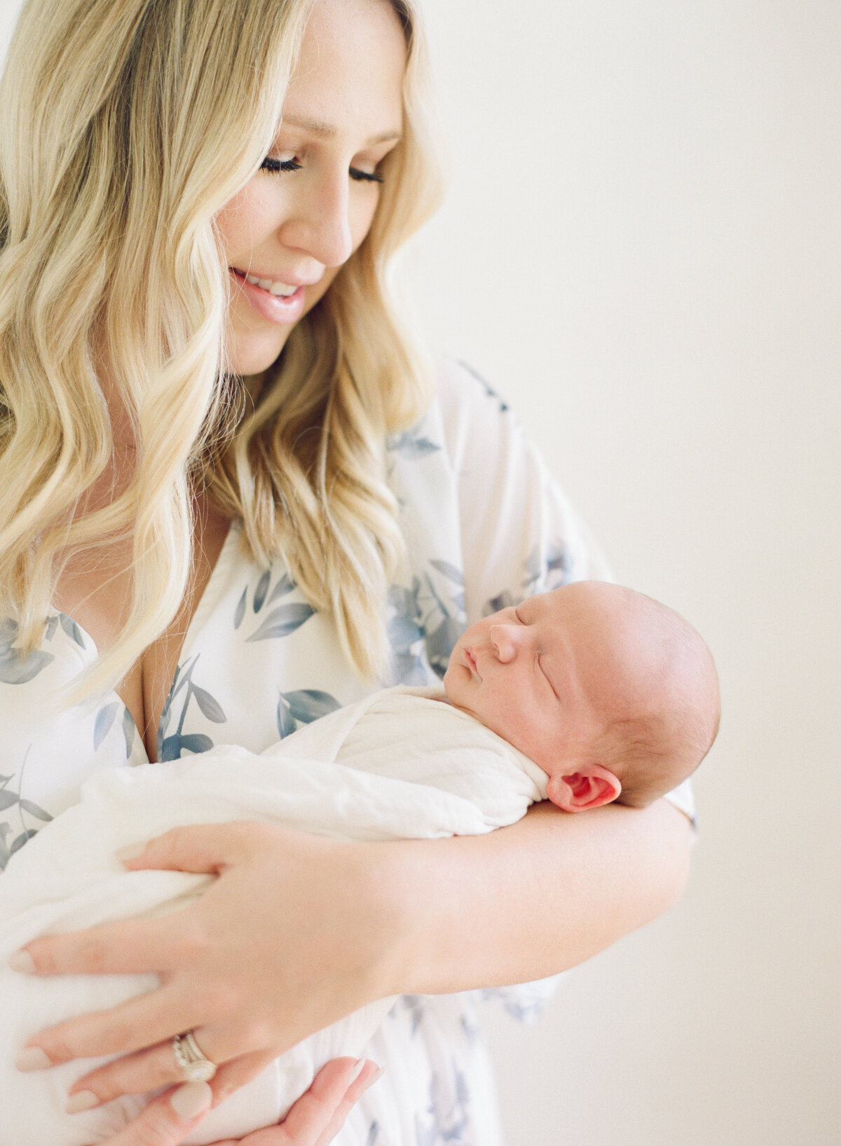 New mom holding her son and looking down lovingly at him. Image by Raleigh newborn photographer A.J. Dunlap Photography.